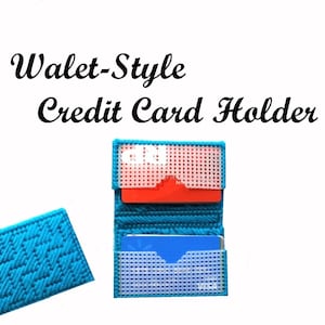 May include: A turquoise blue wallet-style credit card holder with two slots for cards. The holder is made of a woven fabric and has a grid pattern.