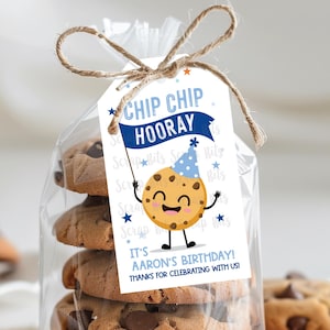 May include: A clear cellophane bag tied with twine, filled with chocolate chip cookies. A tag reads "Chip Chip Hooray! It's Aaron's Birthday! Thanks for celebrating with us!" A cartoon cookie character is on the tag, wearing a party hat.