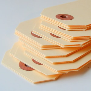 Peut inclure: Une pile d'étiquettes en papier beige clair avec un cercle brun au centre de chaque étiquette.