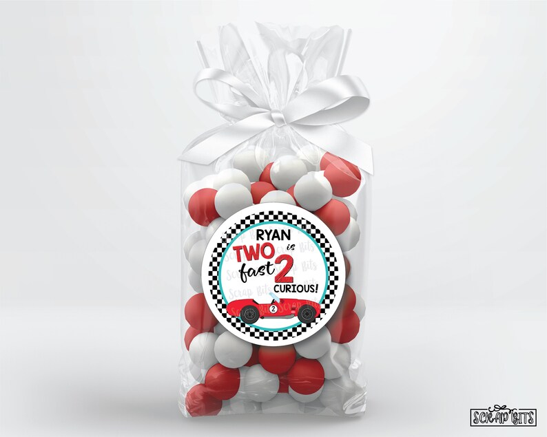 May include: A red and white favor bag with a round sticker that says "Ryan is Two fast 2 curious!" with a red race car on it. The bag is filled with red and white candy.