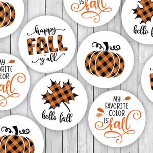 May include: A collection of white circular stickers with fall-themed designs. The stickers feature pumpkins, maple leaves, and phrases like "Happy Fall y'all" and "My favorite color is fall" in orange and black.
