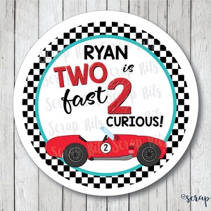 May include: A white circle with a black and white checkered border. The center of the circle has a red race car with the text "RYAN is TWO fast 2 CURIOUS!" in black and red lettering.