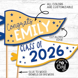 May include: Two graduation pennant signs with text. The top pennant says "Congrats EMILY" in blue script on a yellow background, with blue stars. The bottom pennant says "CLASS OF 2026" in blue on a yellow background, with blue stars. The signs are on wooden dowels.