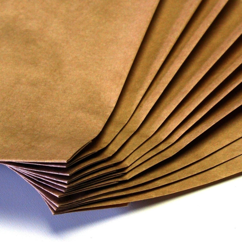 Op de afbeelding: Een stapel bruine papieren zakken gevouwen in een waaier. De zakken zijn gemaakt van getextureerd papier en hebben een natuurlijke, rustieke uitstraling.