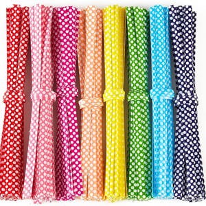 May include: A collection of colorful paper straws in various shades, including red, pink, magenta, orange, yellow, green, blue, and navy. Each straw is adorned with white polka dots and tied with a matching ribbon, perfect for parties and celebrations.