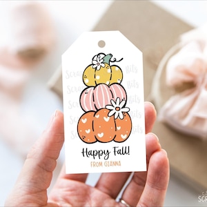 Könnte beinhalten: Ein weißes, rechteckiges Geschenkanhänger-Etikett mit einer Illustration von drei gestapelten Kürbissen in Gelb, Rosa und Orange. Die Kürbisse sind mit kleinen weißen Herzen und Blumen verziert. Der Text lautet Happy Fall! und FROM GIANNA.