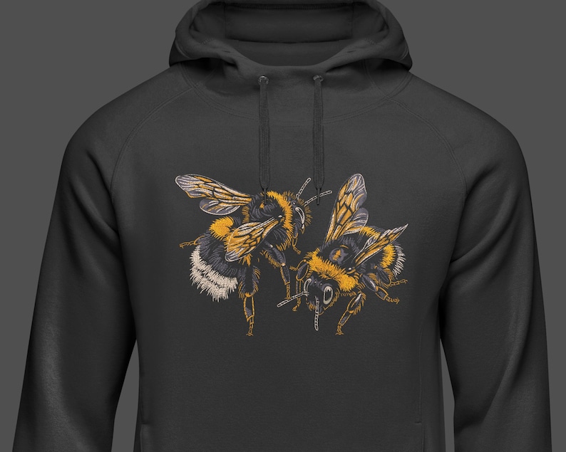 May include: A black hooded sweatshirt featuring a detailed illustration of two bumblebees. The bees are depicted with yellow, black, and white markings, with intricate wing details. The hoodie has a drawstring and a kangaroo pocket.