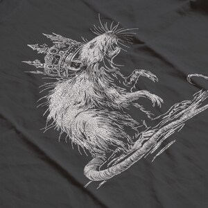 May include: A detailed, embroidered design of a rat wearing a crown, rendered in white thread on a dark gray fabric. The rat is depicted with its mouth open, and its tail curves gracefully. The design has a textured, hand-stitched appearance.