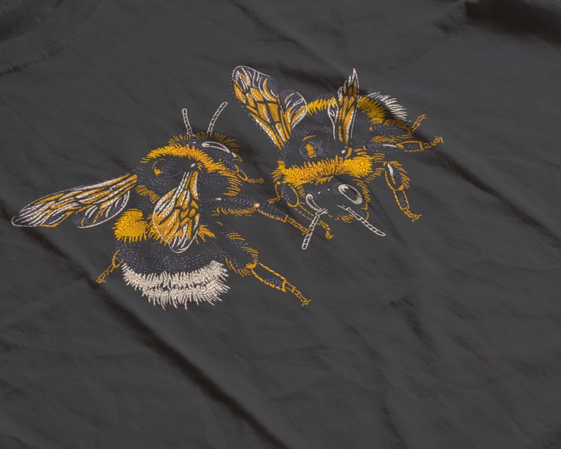May include: Embroidered design of two bumblebees in yellow, black, and white on a dark gray background. The bees are detailed with visible wings, legs, and body segments, showcasing a nature-inspired theme.