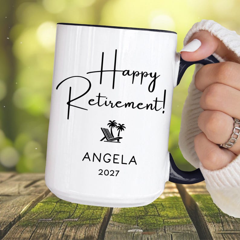 A person is holding a white mug with the text "Happy Retirement!" printed on it.