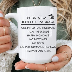 A person holding a white mug with text on it, which appears to be a benefits package description.