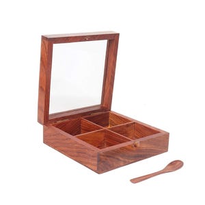 Puede incluir: Una caja de madera con tapa de vidrio y cuatro compartimentos. La caja est&aacute; hecha de madera oscura con un tono rojizo. Se incluye una peque&ntilde;a cuchara de madera.
