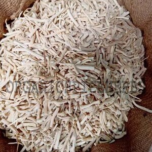 May include: A burlap sack filled with a large quantity of light-colored, dried, and chopped plant roots. The roots are a pale beige color and appear to be evenly cut into small pieces. The sack is brown and has a rough texture.