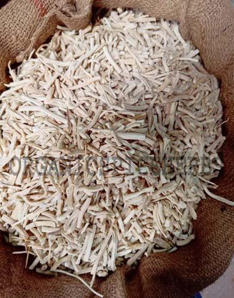 May include: A burlap sack filled with a large quantity of light-colored, dried, and chopped plant roots. The roots are a pale beige color and appear to be evenly cut into small pieces. The sack is brown and has a rough texture.