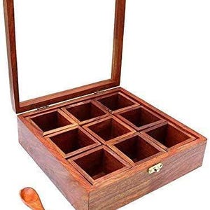 Puede incluir: Una caja de especias de madera con tapa de vidrio y ocho compartimentos. La caja est&aacute; hecha de madera oscura y tiene un cierre de lat&oacute;n. Se incluye una peque&ntilde;a cuchara de madera.