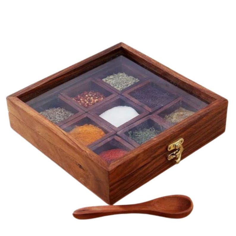 Puede incluir: Una caja de especias de madera con tapa de vidrio y ocho compartimentos. La caja est&aacute; llena de diversas especias, incluyendo sal, pimienta y hierbas. Se incluye una cuchara de madera.