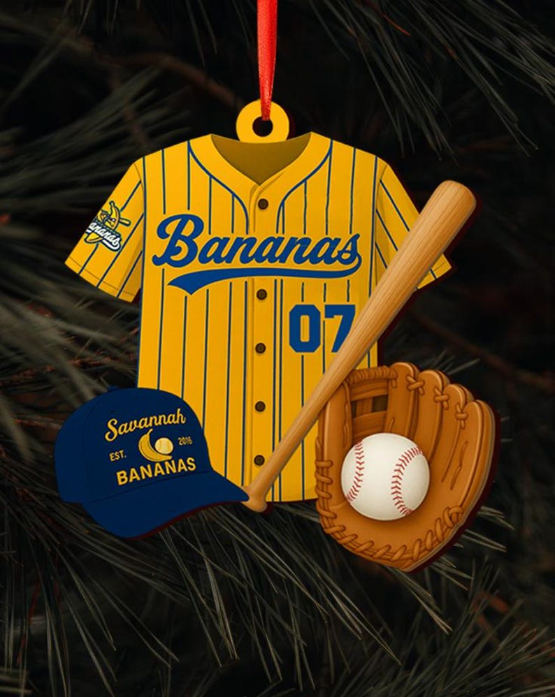 Pode incluir: Enfeite de Natal com tema de beisebol. Apresenta uma camisa amarela com riscas azuis e a palavra "Bananas". Inclui um bast&atilde;o de beisebol, uma luva, uma bola de beisebol e um bon&eacute; azul com o texto "Savannah Bananas". A camisa tem o n&uacute;mero "07".