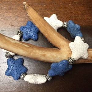 May include: A blue and white star-shaped bracelet with silver beads. The bracelet is made of lava rock and is a great accessory for any occasion.