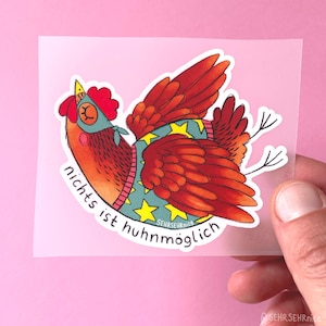 Könnte beinhalten: Ein Aufkleber mit einem roten Huhn, das einen blauen Pullover mit gelben Sternen und eine blaue Augenmaske trägt. Das Huhn hat die Flügel ausgebreitet und fliegt. Unter dem Huhn steht der Text "nichts ist huhnmöglich" in schwarzen Buchstaben.