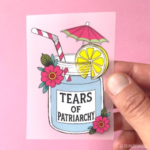 Könnte beinhalten: Ein rechteckiger Aufkleber mit einem hellblauen Glas, das mit Flüssigkeit gefüllt ist und den schwarzen Text TEARS OF PATRIARCHY trägt. Das Glas ist mit einem rosa-weiß gestreiften Strohhalm, einer gelben Zitronenscheibe, einem rosa Schirmchen und rosa Blumen verziert.