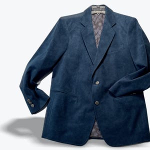 Peut inclure: Un blazer en daim bleu foncé doté d'un revers cranté, de deux boutons sur le devant et de trois petits boutons sur chaque poignet. L'intérieur est doublé d'un tissu gris à motif cachemire subtil, visible au col et à l'ouverture avant.