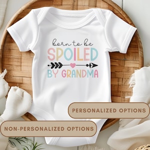 May include: White baby onesie with a colorful graphic that says "born to be spoiled by grandma" with an arrow and a heart.