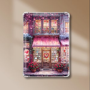 Pode incluir: Uma capa retangular para tablet com uma ilustração detalhada da fachada de uma livraria. A cena inclui um toldo rosa, prateleiras cheias de livros, vasos de rosas vermelhas e corações cor-de-rosa flutuantes num edifício de tijolo.