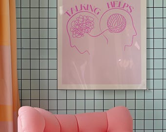 May include: A pink framed print with the words "TALKING HELPS" and two head silhouettes, one with a tangled brain and the other with a ball of yarn. A pink tufted armchair sits below the print, with a light blue tiled wall in the background.