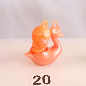 May include: A display of small, colorful swan figurines. Each swan has a small figure riding in the center. The swans are pink, orange, and green. Numbers 19, 20, and 21 are printed below the swans.