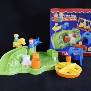 May include: A vintage Fisher-Price Play Family playset. The set includes a green playground with a slide, figures, and other accessories. The box shows illustrations of the playset. The set includes a yellow and orange merry-go-round.