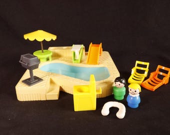 Puede incluir: Un juego de juguetes vintage con una piscina, un tobogán, tumbonas y figuras. Incluye una barbacoa y una sombrilla amarilla. La piscina está llena de agua azul y el juego es de plástico.