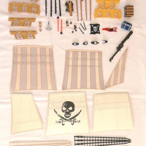 May include: A flat-lay image of a pirate ship toy set, featuring sails, cannons, and rigging. The sails have a skull and crossbones emblem. The set includes a small boat and numerous small components for assembly.