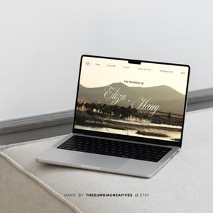 May include: A silver laptop displaying a wedding website design. The screen shows the words "The Wedding of Eliza & Harry" over a landscape image. The laptop is on a light-colored surface, with the text "MADE BY THEEUNOIACREATIVES @ ETSY" at the bottom.