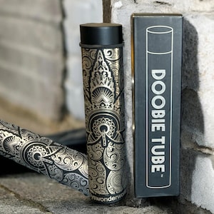 May include: Two black and gold patterned tubes, one with the text "DOOBIE TUBE" printed on the side. The tubes are made of metal and have a decorative design.