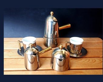 May include: A silver and gold coffee and tea set with a coffee pot, creamer, sugar bowl, and two cups and saucers.