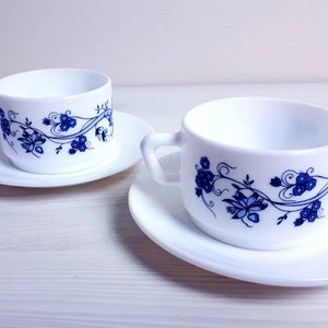 May include: Two white ceramic teacups with blue floral designs and matching saucers.