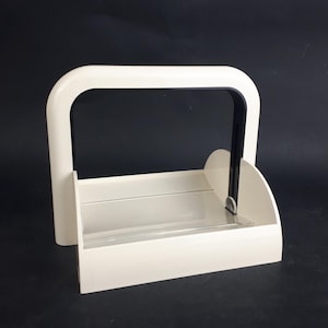 Op de afbeelding: Een witte, rechthoekige organizer met een gebogen handvat en een zwart interieur. De organizer heeft een doorzichtige, horizontale verdeler en afgeronde zijsteunen. De achtergrond is zwart.