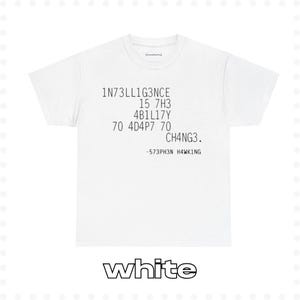 May include: White t-shirt with black text that reads "1N73LL1G3NCE 15 7H3 4B1LL17Y 70 4D4P7 70 CH4NG3. -573PH3N HAWK1NG"