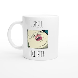 May include: White ceramic coffee mug with a black and white illustration of a person's face with the text "I smell like beef" printed on the mug.