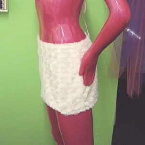 May include: A white faux fur bikini top and skirt set. The top is a triangle style with pink straps. The skirt is a mini skirt with a high waist.