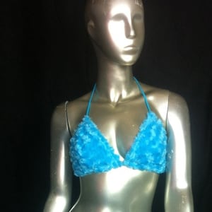 May include: A turquoise blue halter top bikini with a textured, fluffy appearance. The triangle cups are connected by a thin, matching blue string that goes around the neck. The bikini is displayed on a mannequin against a black background.