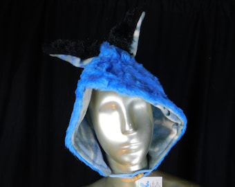 May include: A blue faux fur hood with black ear accents. The hood is lined with a light blue and white patterned fabric. The hood is displayed on a mannequin head.