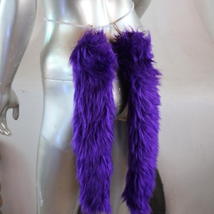 May include: Two long, purple, fluffy tails attached to a white strap. The tails are made of faux fur and are about 12 inches long.