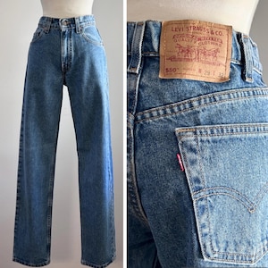 May include: Medium-wash blue denim jeans with a high-waisted fit and straight legs. The back features a tan leather patch with the text Levi Strauss & Co. 550 Relaxed Fit W 29 L 32 and a small red tab on the back pocket with the Levi's logo.