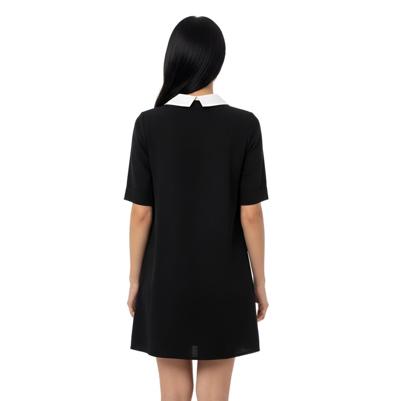 Puede incluir: Un vestido negro con cuello blanco y mangas cortas. El vestido es de dise&ntilde;o sencillo y cl&aacute;sico, adecuado para diversas ocasiones. La modelo est&aacute; de espaldas a la c&aacute;mara.