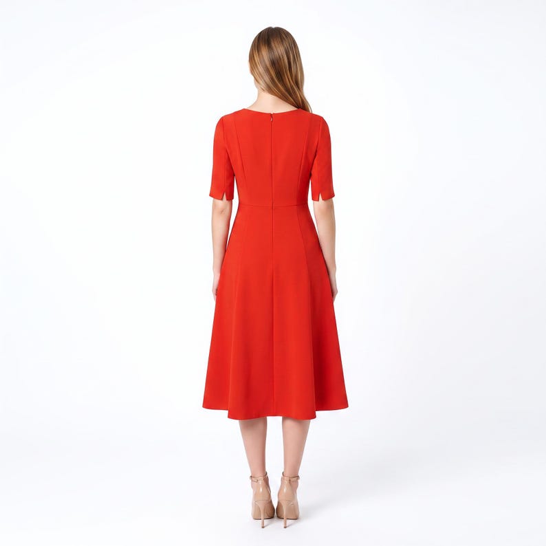 May include: A vibrant red midi dress featuring short sleeves with small slits at the cuffs, a round neckline, and a fitted bodice that transitions into a flared skirt. The back of the dress includes a vertical seam and a concealed zipper closure.