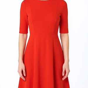 May include: A vibrant red midi dress featuring a round neckline, elbow-length sleeves, and a fitted bodice that transitions into a flared, A-line skirt. The garment is constructed with vertical seam detailing along the front torso and waist.