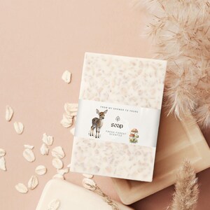May include: A white bar of soap with a light brown deer and mushrooms on the label. The label reads "From my shower to yours" and "Soap Fresh Forest Scented".