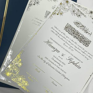 Puede incluir: Un certificado de boda blanco con detalles florales dorados y caligrafía. El texto dice "This Agreement is to Certify the Marriage of Hamza & Sophia" e incluye la fecha "2nd January 2024" y la ubicación "In the city of Leicester, United Kingdom".