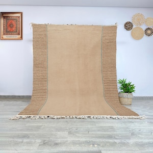 Hand knotted Moroccan Beni Ourain rug in neutral beige with minimalist design, featuring soft striped textured borders, woven in wool by Berber artisans, perfect for Japandi, Scandinavian, or modern interiors.